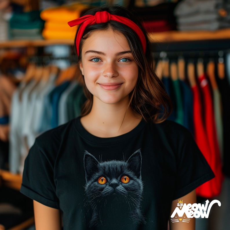 Pretty brunette girl wearing a black t-shirt with a British Shorthair cat looking upwards with its amber eyes.