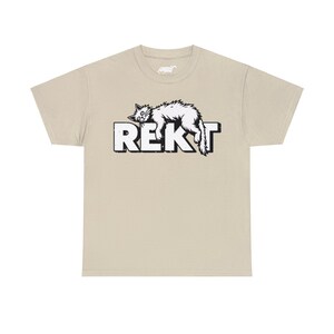 Sand Colored unisex T-shirt featuring humorous white “REKT” text topped with an illustration of an exhausted cat lying sprawled out, capturing gamer and meme culture vibes.