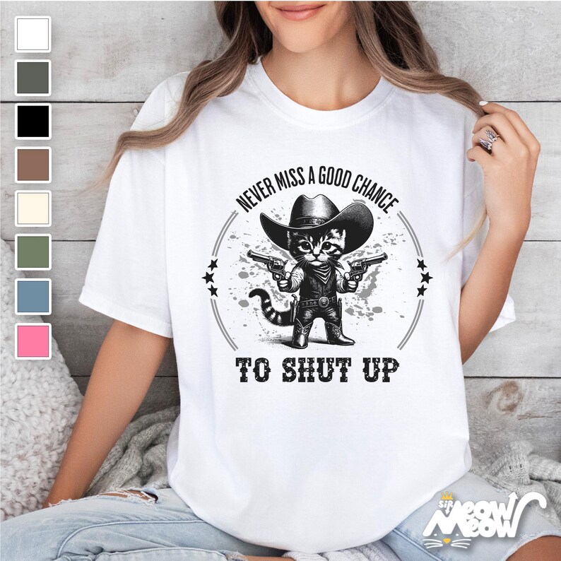 K&ouml;nnte beinhalten: Wei&szlig;es T-Shirt mit einer schwarz-wei&szlig;en Illustration einer Katze, die einen Cowboyhut tr&auml;gt und zwei Pistolen h&auml;lt. Der Text "Never miss a good chance to shut up" ist auf dem T-Shirt aufgedruckt.