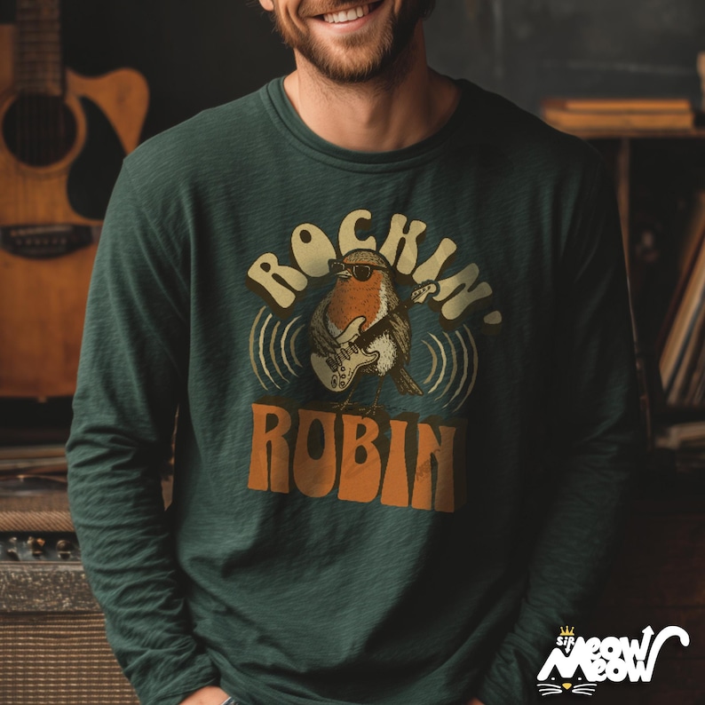 K&ouml;nnte beinhalten: Dunkelgr&uuml;nes Langarmshirt mit dem Text "Rockin' Robin" und einem Cartoon-Rotkehlchen, das E-Gitarre spielt. Das Rotkehlchen tr&auml;gt eine Sonnenbrille. Das Shirt hat ein Retro-Design.