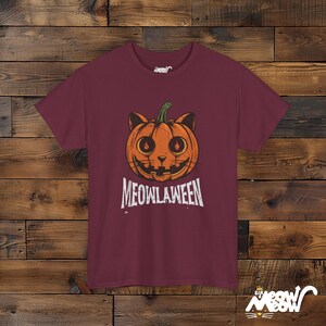 May include: Burgundy t-shirt with a Halloween design. The graphic shows a jack-o'-lantern with cat ears and the word "MEOWLAWEEN" in white. The t-shirt has short sleeves and a crew neck.