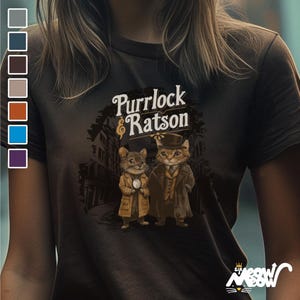 May include: A dark gray t-shirt with a graphic of two cats wearing hats and the text "Purrlock & Ratson".
