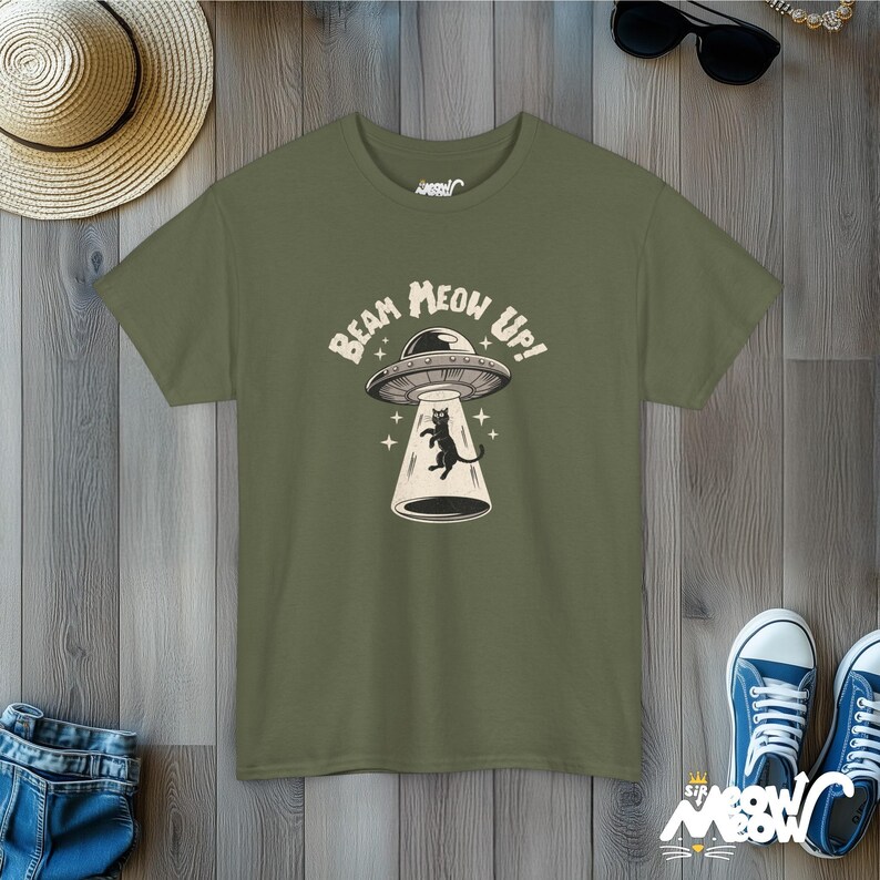 May include: A green t-shirt with a black cat in a UFO. The text on the shirt reads "Beam Meow Up!"