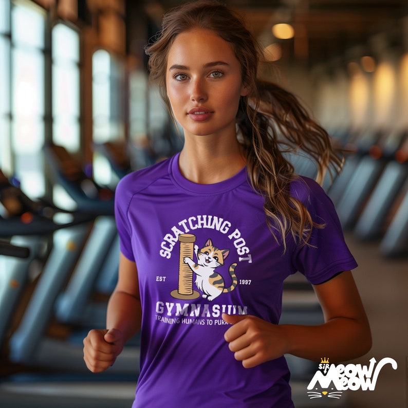 May include: Purple athletic shirt with a cartoon cat scratching a scratching post. The shirt says "Scratching Post Est. 1997 Gymnasium Training Humans to Purr."