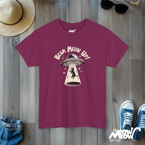 May include: A maroon t-shirt with a black cat in a flying saucer. The text on the shirt reads "Beam Meow Up!"