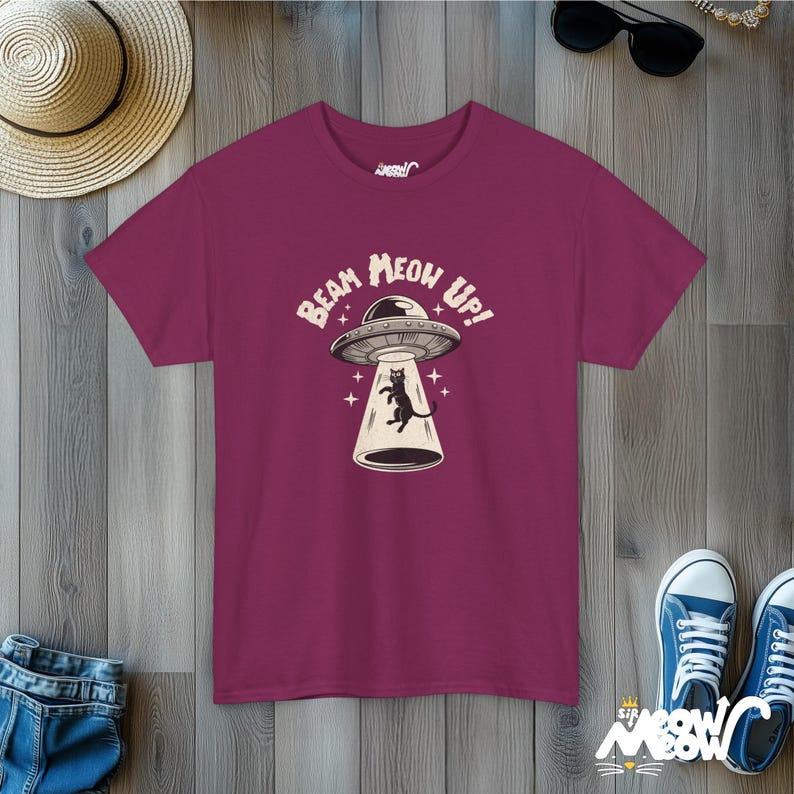 May include: A maroon t-shirt with a black cat in a flying saucer. The text on the shirt reads "Beam Meow Up!"