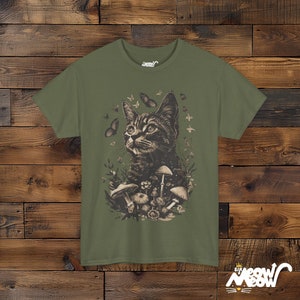 Vintage style t-shirt print of a cat in the woodlands surrounded by wildflowers, mushrooms and butterflies. Army green tee.
