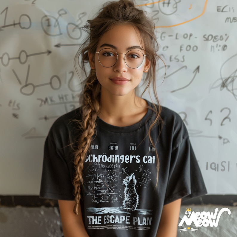 May include: A woman wearing round glasses and a black t-shirt with a white graphic of a cat and the text "Schr&ouml;dinger's cat" and "The Escape Plan".