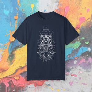 May include: Navy blue t-shirt featuring a white graphic of a cat's face, geometric shapes, and a lotus flower. The design is centered on the front of the shirt. The shirt is made of a soft material.
