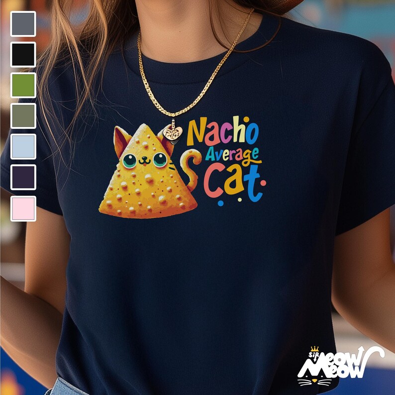 May include: A navy blue t-shirt with a colorful graphic of a cat-shaped nacho. The text "Nacho Average Cat" is printed in rainbow colors on the shirt.