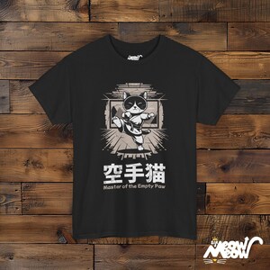 May include: Black t-shirt with a graphic of a black and white cat in a karate pose. The text "空手猫 Master of the Empty Paw" is printed below the cat.