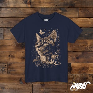 Vintage style t-shirt print of a cat in the woodlands surrounded by wildflowers, mushrooms and butterflies. Navy tee.