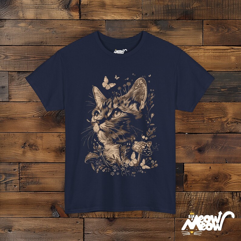 Vintage style t-shirt print of a cat in the woodlands surrounded by wildflowers, mushrooms and butterflies. Navy tee.