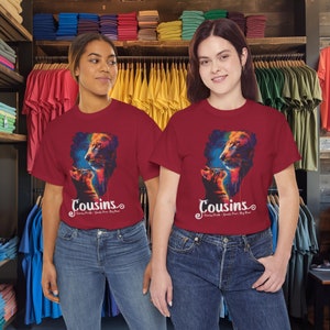 May include: Two red t-shirts with a colorful graphic of a lion and a cat with the text "Cousins Family Pride - Dual Pure - Big Roar" printed on the front.