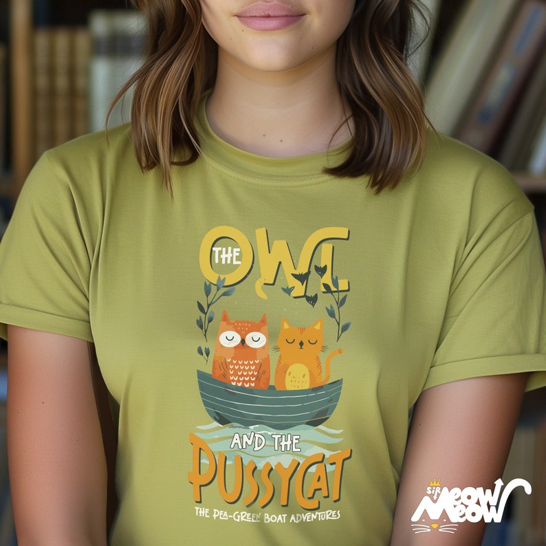 May include: A green t-shirt with a graphic design of an owl and a cat in a boat. The text on the shirt reads "The Owl and the Pussycat, The Pea-Green Boat Adventures".