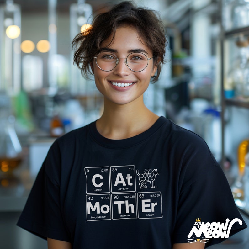 May include: A black t-shirt with a white graphic of the periodic table elements, spelling out "Cat Mother" with a cat illustration. The text "Sip Meow Meow" is printed on the bottom right corner of the shirt.