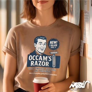 K&ouml;nnte beinhalten: Ein beiges T-Shirt mit einem Retro-Grafikdesign. Es zeigt einen l&auml;chelnden Mann, einen Rasierer und die Worte "Occam's Razor". Das Design enth&auml;lt die S&auml;tze "New! 1 Blade (Still 1)" und "When Simplest Solutions Are Preferred."