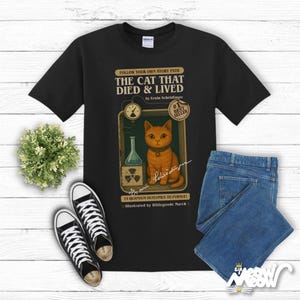 May include: Black t-shirt with a vintage-style illustration of a cat in a glass jar with a radioactive symbol. The text reads "The Cat That Died & Lived" by Erwin Schrödinger.  #1 Best Seller. 15 Quantum Outcomes to Pursue! Illustrated by Hildegunde March.