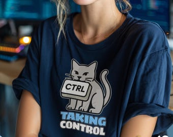 May include: Navy blue t-shirt featuring a gray cat holding a "CTRL" key. Below the cat is the text "TAKING CONTROL" in white and blue. The shirt has a relaxed fit and short sleeves. The Sir Meow logo is in the bottom right corner.