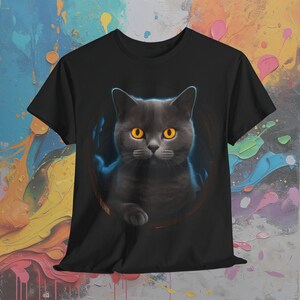 May include: Black t-shirt with a graphic of a gray cat with bright orange eyes peering out of a circle.