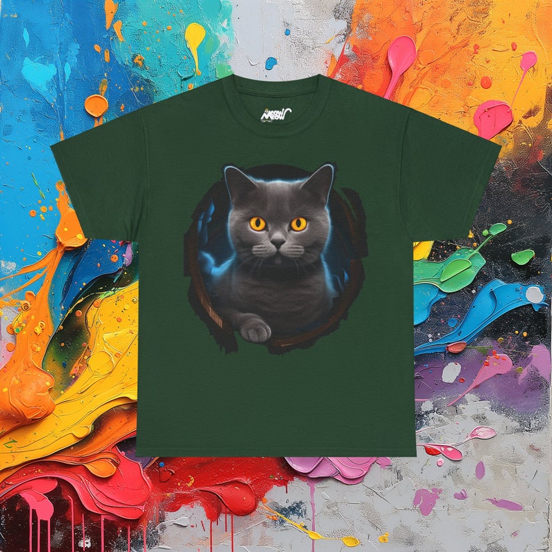 May include: A dark green t-shirt with a graphic of a gray cat with yellow eyes peering out from a hole. The cat is looking directly at the viewer.