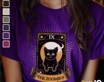 Może przedstawiać: Fioletowy T-shirt z ilustracją czarnego kota na wzorze karty tarota. Karta zawiera napis "IX The Zoomies" oraz "Channel your chaos, embrace the feline frenzy".