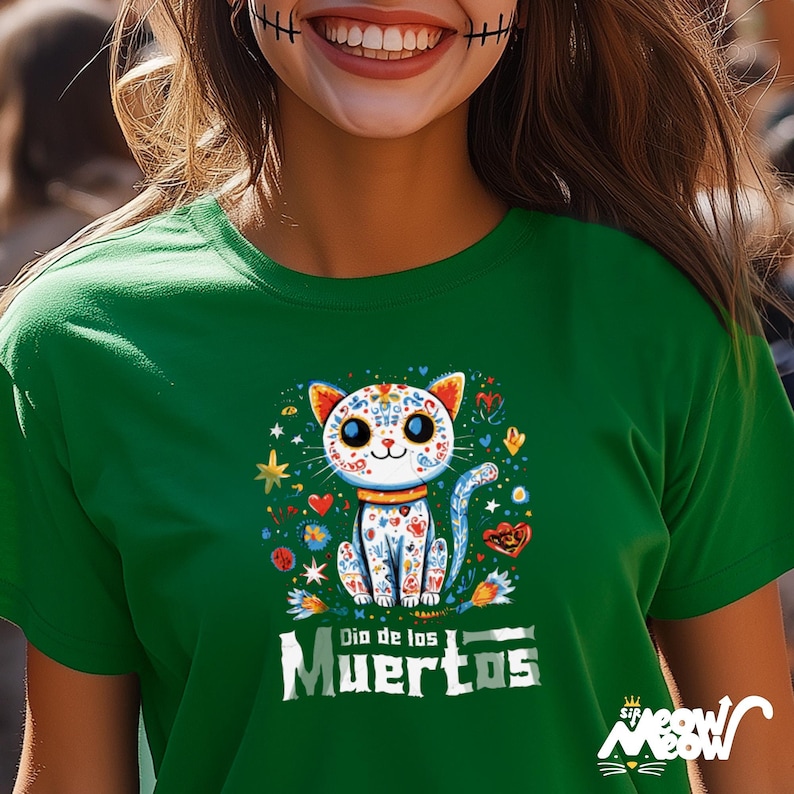 May include: Green t-shirt featuring a colorful cat design with floral and heart accents, and the text "Dia de los Muertos". The cat has a sugar skull design. The shirt also has the text "Sip Meow Meow".