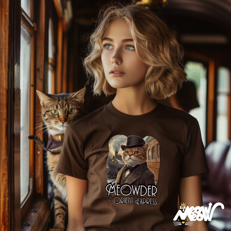 May include: A brown t-shirt with a cat illustration in a suit and top hat, with the text "MEOWDER the ORIENT EXPRESS". A tabby cat with a purple collar is visible. The image is set in a vintage train carriage.