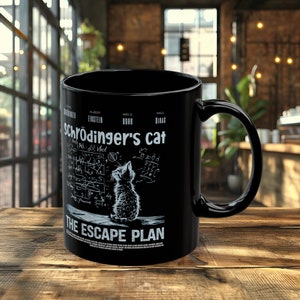 May include: Black ceramic coffee mug with a white graphic of a cat looking up at a chalkboard with equations and the text "Schrödinger's cat The Escape Plan".