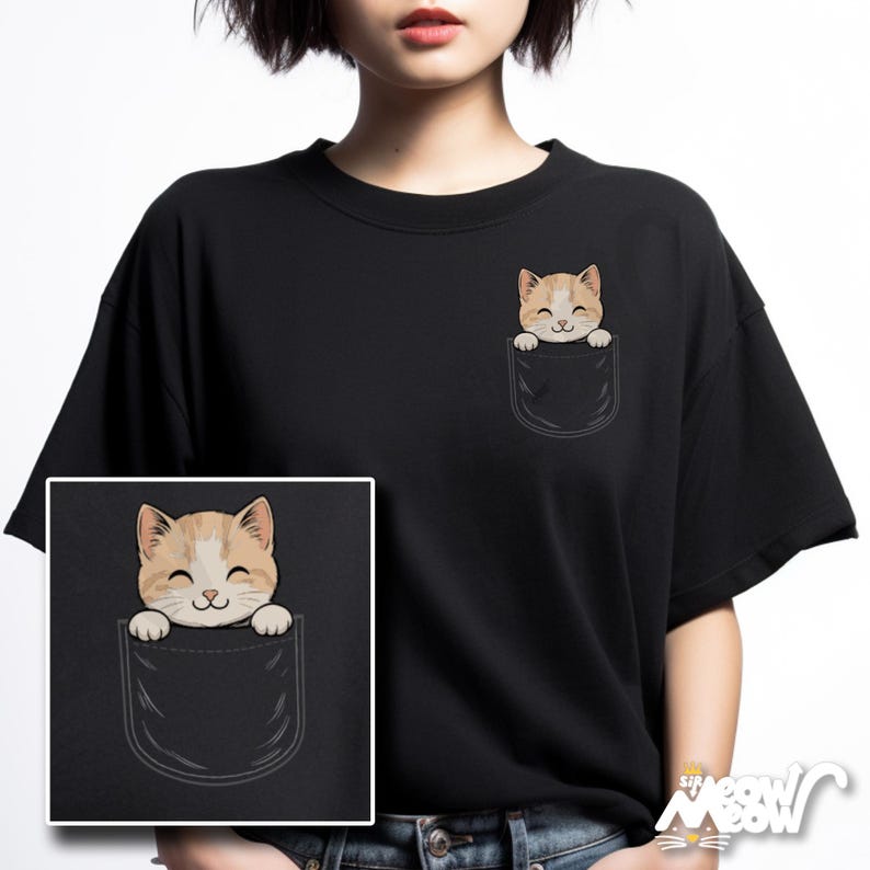 May include: Black t-shirt featuring a cartoon cat peeking out of a pocket. The cat has tan and white fur and a smiling face. The pocket is black and has a curved bottom. The shirt is a crew neck.