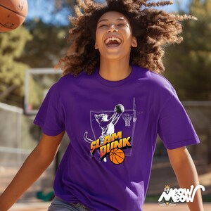 May include: A purple t-shirt with a graphic of a cat dunking a basketball. The text "Slam Dunk" is printed on the shirt. The cat is wearing a basketball jersey and shorts.