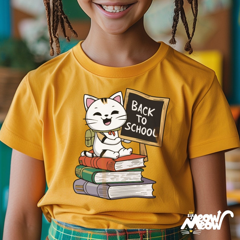 May include: A yellow t-shirt with a cartoon cat wearing a backpack and holding a chalkboard that says "Back to School". The cat is sitting on a stack of books.