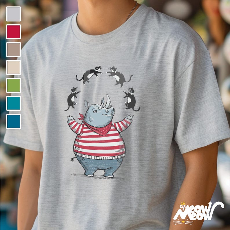 May include: A gray t-shirt with a cartoon illustration of a rhinoceros wearing a red and white striped shirt and a red bandana. Four black cats are jumping around the rhinoceros.