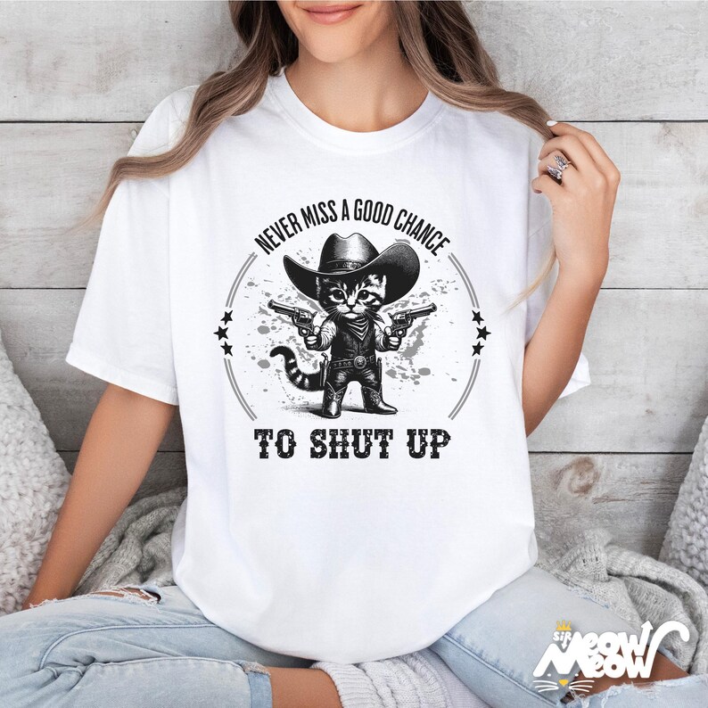 K&ouml;nnte beinhalten: Wei&szlig;es T-Shirt mit einer schwarz-wei&szlig;en Grafik eines Katers mit Cowboyhut und zwei Pistolen. Der Text auf dem Shirt lautet "Never miss a good chance to shut up."