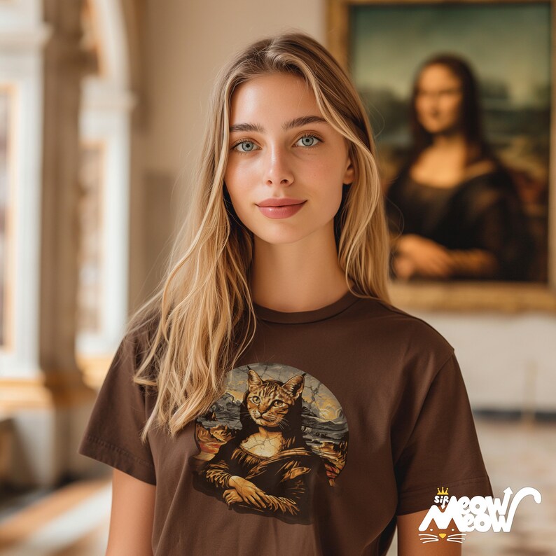 Peut inclure: T-shirt marron avec une parodie f&eacute;line du tableau de la Joconde. Le t-shirt a un col rond et des manches courtes. Le texte "Sir Meow Meow" est imprim&eacute; en bas &agrave; droite du t-shirt.