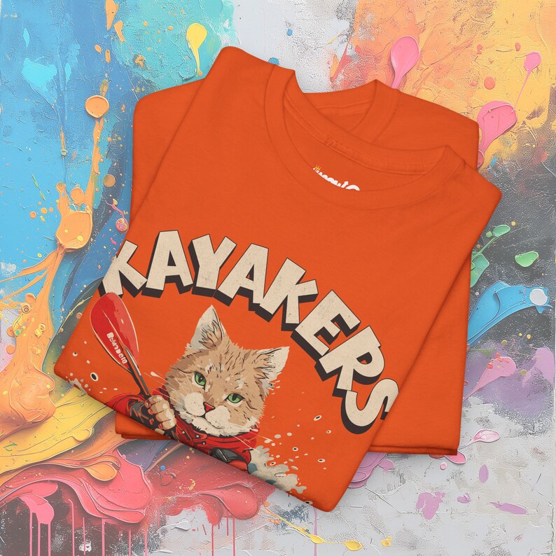 May include: Orange t-shirt with a graphic of a cat holding a paddle and the word "KAYAKERS" in large letters.