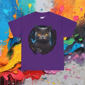 May include: Purple t-shirt with a graphic of a gray cat with yellow eyes peeking out of a hole. The cat is looking directly at the viewer.