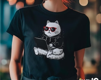 May include: Black t-shirt featuring a white cat wearing red sunglasses and a black hoodie, sitting and using a laptop. The cat illustration has a minimalist design. The shirt has the text "sip meow" in a stylized font at the bottom.