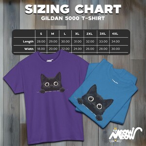 May include: Sizing chart for Gildan 5000 t-shirts, showing measurements in inches for length and width. Sizes range from S to 4XL. The chart is displayed on a wooden background with two t-shirts featuring a black cat peeking out from behind a fold of fabric. One t-shirt is purple and the other is blue.