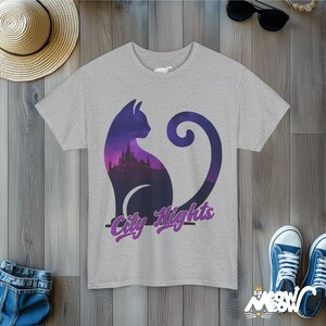 Pode incluir: Uma camiseta cinza mescla com uma silhueta roxa de um gato com um horizonte da cidade dentro. O texto "City Nights" &eacute; impresso em roxo abaixo do gato.