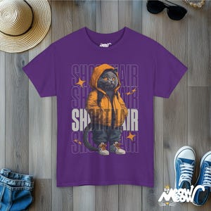 Humanized British Shorthair Cat standing up wearing a yellow hoodie and white and gray sneakers. Behind the cat is a stack of the word "Shorthair". The design appears on a woman wearing a purple tee.