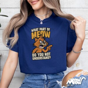 Puede incluir: Una camiseta azul con un gato de dibujos animados y el texto "&iquest;Qu&eacute; parte de MIAU no entiendes?"