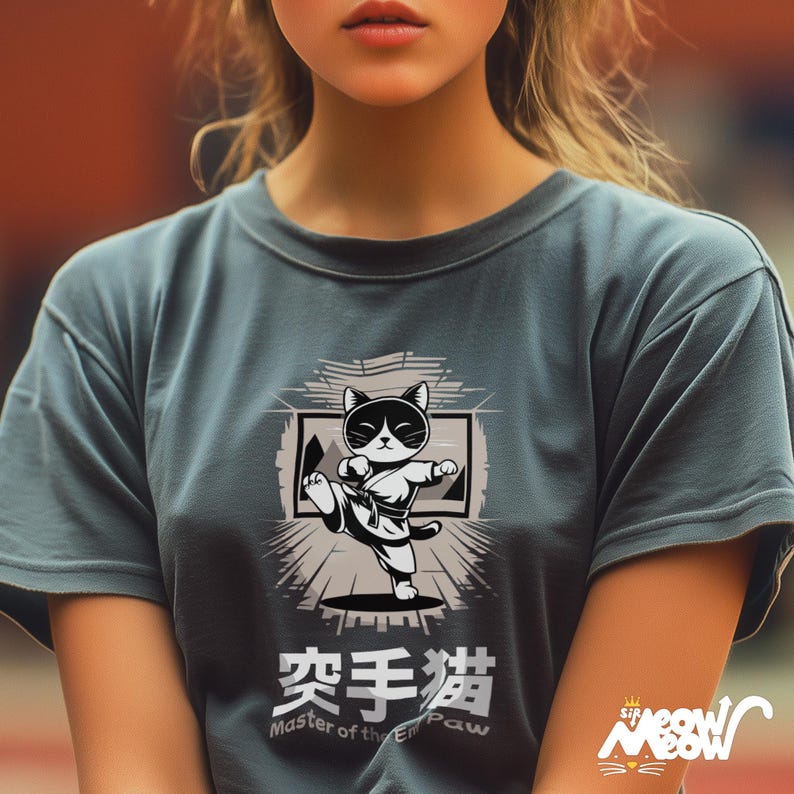 May include: A teal blue t-shirt with a black and white illustration of a cat in a karate pose. The text "Master of the Empty Paw" is below the image, and the text "空手猫" is above the image.