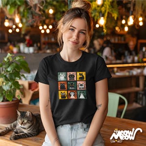 May include: Black t-shirt with a colourful stamp design showcasing different cat illustrations. The shirt has a crew neck and short sleeves. The bottom right corner of the shirt has the text "sip meow meow" with a cat face logo.