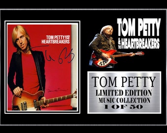 May include: A black and white photo of Tom Petty and the Heartbreakers. The photo is signed by Tom Petty. The photo is part of a limited edition music collection. The text "Tom Petty and the Heartbreakers" is printed in white on a black background. The text "Tom Petty Limited Edition Music Collection 1 of 50" is printed in white on a silver background.