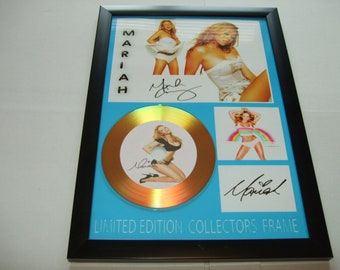 May include: A framed gold disc featuring a picture of Mariah Carey. The disc is signed by Mariah Carey and the frame reads "Limited Edition Collectors Frame".