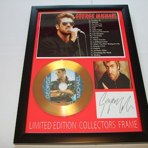 May include: A gold-colored CD with a picture of George Michael on it. The CD is in a red frame with a black border. The frame also includes a picture of George Michael and his signature. The text "LIMITED EDITION COLLECTORS FRAME" is printed on the bottom of the frame.