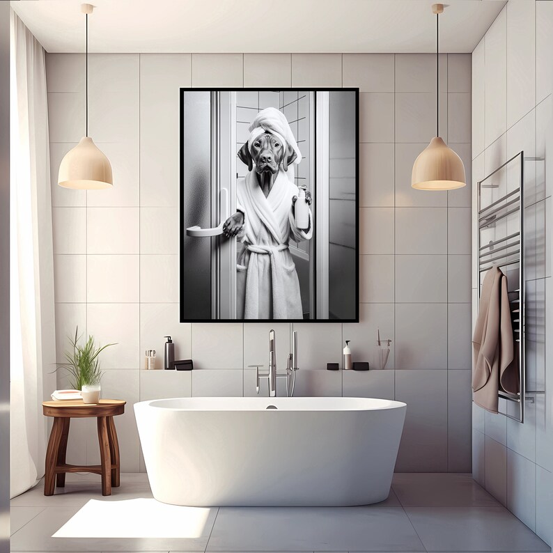 May include: Black and white photo of a dog wearing a white bathrobe and a towel on its head, standing in a bathroom. The dog is holding a bottle of shampoo in its paw.