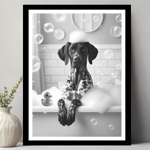 以下が含まれることがあります： バスタブに泡が立っている中で、犬が写っている白黒写真。犬は白い頭をしていて、石鹸の泡で覆われています。黄色いゴム製のオモチャの鴨が水に浮かんでいます。