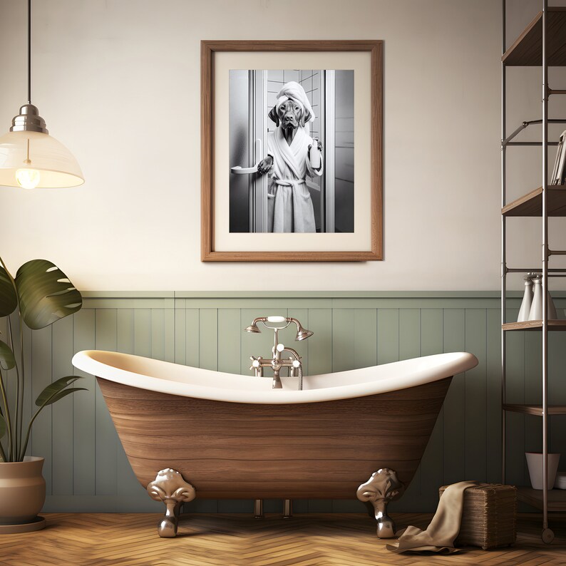 May include: A black and white photo of a dog wearing a white bathrobe and standing in a bathroom doorway. The photo is framed in a wooden frame and hanging on a wall above a wooden bathtub.